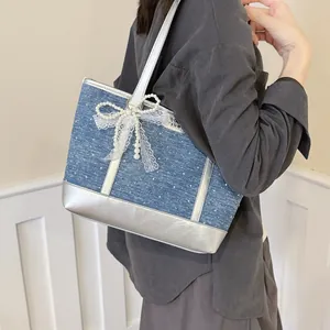 Vue détaillée d'un sac cabas en denim avec garniture argentée et nœud en perles.