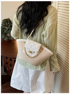 Vue détaillée d'un sac cabas en paille tissée avec rabat en cuir blanc matelassé et chaîne