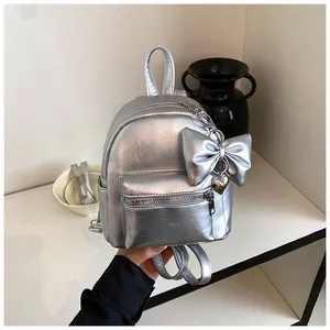 Nahaufnahme eines silbernen metallischen Minirucksacks mit dekorativer Schleife und Herz.