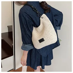 Detail of cream woven bucket bag with black handle on denim outfit