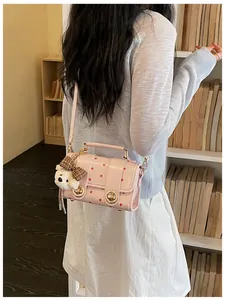 Vintage pink polka-dot small crossbody bag featuring a cute plush bear charm on a model