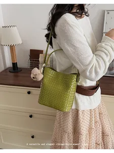 Elegant green woven leather bucket bag with top handle shown on a lifestyle model
