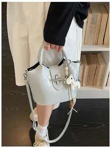 Vue détaillée d'un sac seau bleu clair avec breloque cheval et fermoir rotatif en métal.