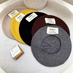 Close-up of diverse knitted berets featuring 'Season 13' patches on a textured surface.