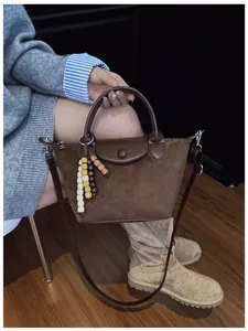 Vue détaillée d'un sac à main marron en daim avec des breloques en perles.