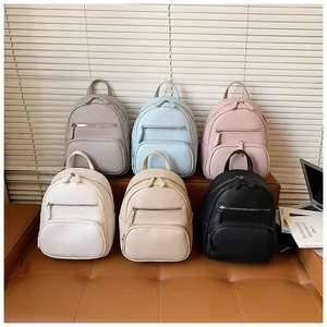 Variety of six colors of minimalist faux leather mini backpacks for women shown on a sofa