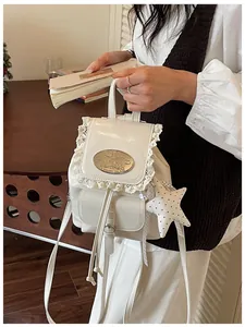 Detailopname van crèmekleurige rugzak met kant en sterren bedeltje eraan.