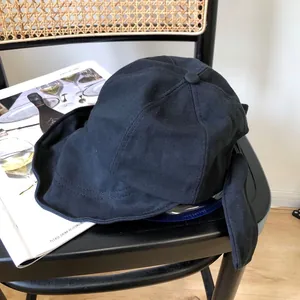 Detalle de un sombrero de sol negro de ala ancha con un elegante lazo en la parte posterior.