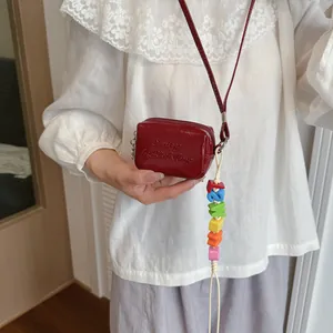 Detail view of mini red patent leather crossbody bag with colorful bead charm