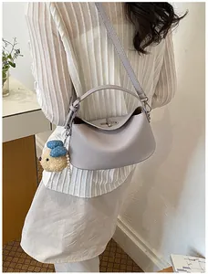 Elegant lavender textured leather bucket bag shown as a crossbody bag with plush charm
