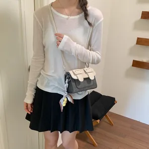 Close-up of a contrast design crossbody bag worn with a casual outfit and silk scarf