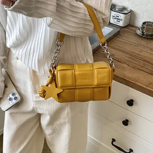 Close-up of yellow woven padded leather shoulder bag with star charm