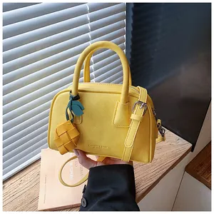 Close-up detail of the vibrant yellow leather pillow handbag featuring a chic woven charm accessory.