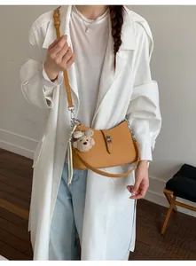 Elegante borsa sottobraccio giallo senape da donna con ciondolo a orsetto e dettagli argentati