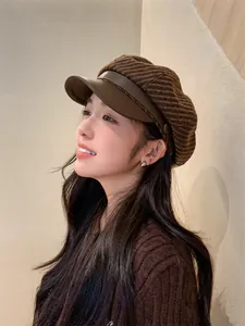 Side view of a vintage brown plaid newsboy cap with leather brim on a female model