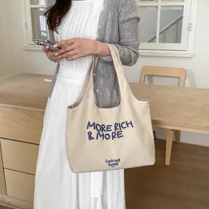 Vista de estilo de vida de un elegante bolso tote de lona beige con bordado azul
