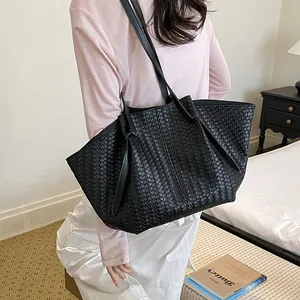 Stylish black woven leather tote bag showcased on shoulder by model in lifestyle setting