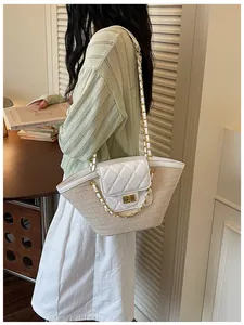 Détail d'un sac panier en paille avec rabat matelassé et chaîne dorée sur mannequin