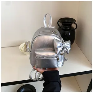 Detailansicht eines silbernen Mini-Rucksacks in Metallic-Optik mit großem Schleifen-Anhänger