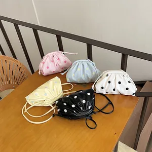 Detailed view of stylish polka dot cloud bags in multiple colors on a rustic wooden table