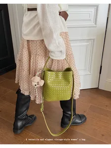 Elegant vintage green woven bucket bag with cute bear pendant accessory on model