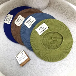 Stack of colorful knitted wool berets with vintage style cloth patches