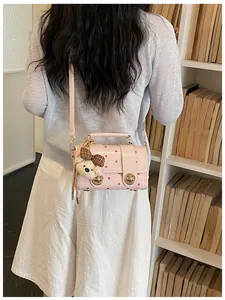 Back view of a retro pink polka-dot crossbody bag featuring a cute bear plush charm