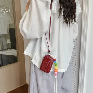 Back view of a model wearing a mini wine red crossbody bag with colorful bead charm