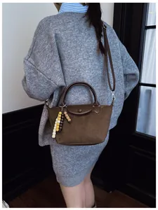 Vue détaillée du sac à main en daim marron avec breloque en perles et bandoulière
