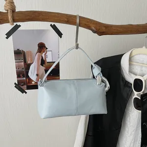 Detailed shot of a light blue vintage pillow bag hanging on a rustic wooden branch.