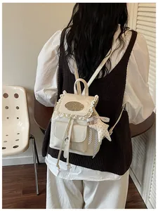 Elegant white backpack with delicate lace trim and star charm shown on a model back