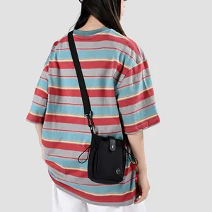 Vue arrière d'un petit sac bandoulière noir porté sur un t-shirt rayé tendance