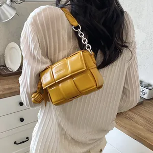 Yellow woven leather underarm bag with silver chain detail on model