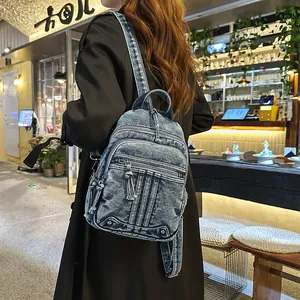 Rear view detail of a trendy washed denim backpack featuring multiple zipper pockets