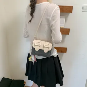 Back view of a stylish color-block small square crossbody bag shown on a model in white top
