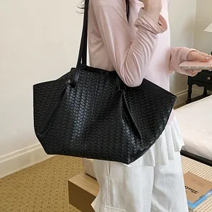 Macro detail of high-quality large black woven tote bag styled on a female model