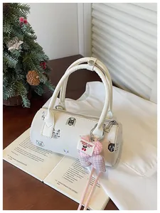 Detailed view of white barrel bag featuring cat prints and heart pendant