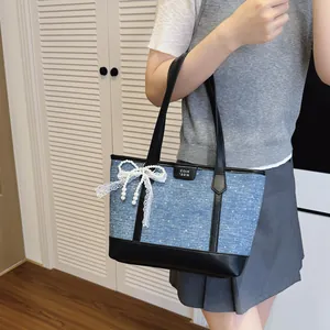 Vue détaillée d'un sac cabas en denim bleu avec nœud en dentelle porté par un mannequin