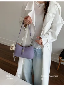 Borsa a spalla sottobraccio viola alla moda con ciondolo a orsetto tenuta da modella