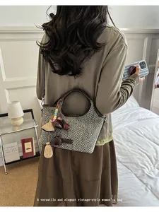 Sac à main en paille tressée de style vintage porté par un mannequin dans une chambre à coucher