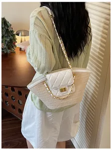 Vue de détail d'un sac panier en paille tressée avec un rabat en cuir matelassé blanc et une chaîne.