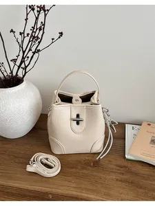 Sac seau vintage en cuir beige avec poignée et bandoulière réglable pour un look rétro chic