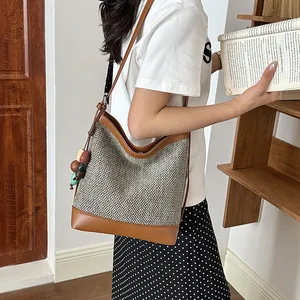 Side view of a woven summer bucket bag with brown leather trim and colorful bead strap.