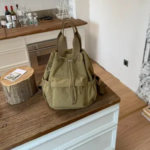 Vista detallada de una mochila minimalista verde oliva con cordón en un mostrador de café