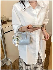 Detail showing a light blue pillow bag with pearl charm held by a woman in a shirt