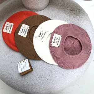 Detailed view showing four colorful knitted wool beret hats with vintage cloth label design