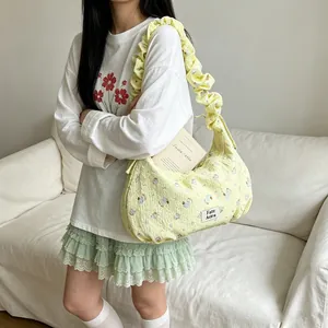 Stylish yellow floral hobo bag with ruffled shoulder strap shown on model for casual summer style