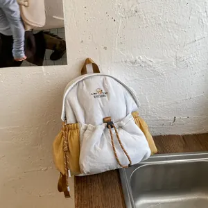 Mochila minimalista blanca y amarilla con cordón y fino detalle de oso bordado