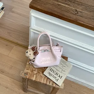 Vista dettagliata di una mini borsa rosa lucida con un simpatico ciondolo a forma di orso