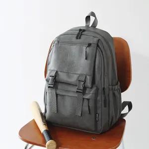 Sac à dos vintage en cuir gris posé sur une chaise en bois avec une batte de baseball